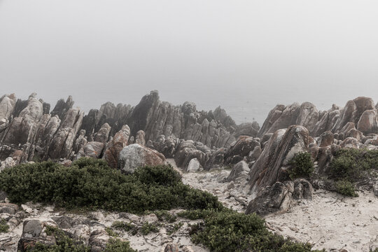 moody landscape of rock formations in sunrise fog, DeKelders, South Africa