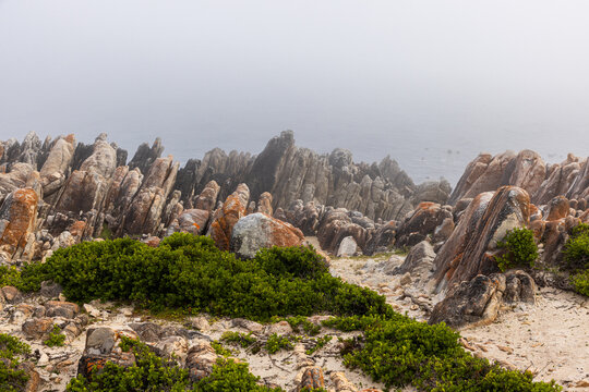 moody landscape of rock formations in sunrise fog, DeKelders, South Africa
