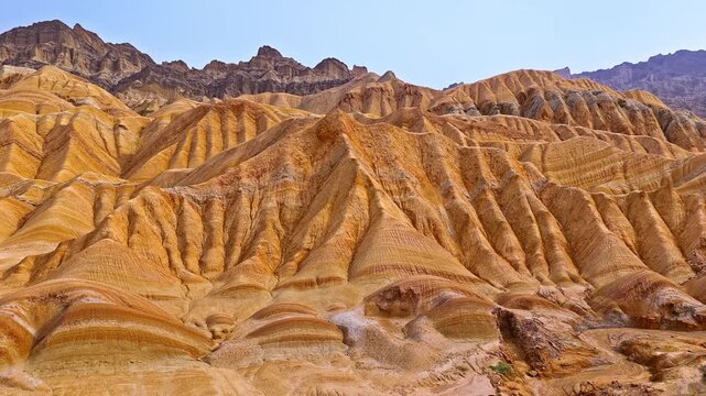 Aerial footage of rugged mountain slopes with colorful geological sandstone patterns in the Red Mountain Stone Forest, Kuqa, Xinjiang, China