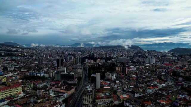 Panoramic Drone View of Quito Ecuador Cityscape with Historic Center, Dense Urban Buildings, Mountain Slopes and Dramatic Cloudy Sky Background