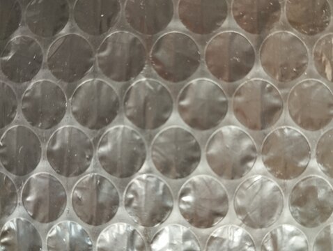 Close up of transparent plastic bubble wrap with round air bubbles pattern, protective packaging material texture background top view
