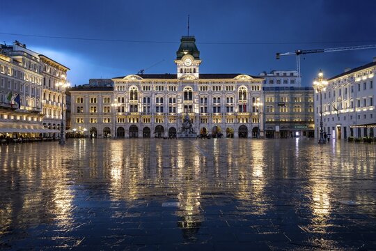 Illuminated square Piazza Unit&agrave; d'Italia, Town Hall, Palazzo Communale, with reflection, dramatic clouds, blue hour, old town, Trieste, Friuli-Venezia Giulia region, Italy