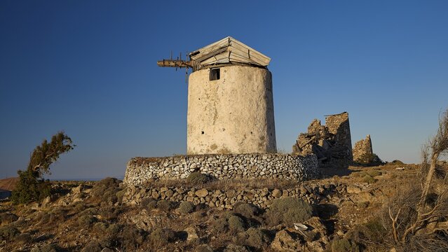Windmill above Chorio on Mount Xaplovouni, An ancient windmill with a stone base in an open, rural landscape, main town on Kimolos, Kimolos, Chorio, Kimolos island, neighboring island of Milos, Cyclades, Greek Islands, Greece