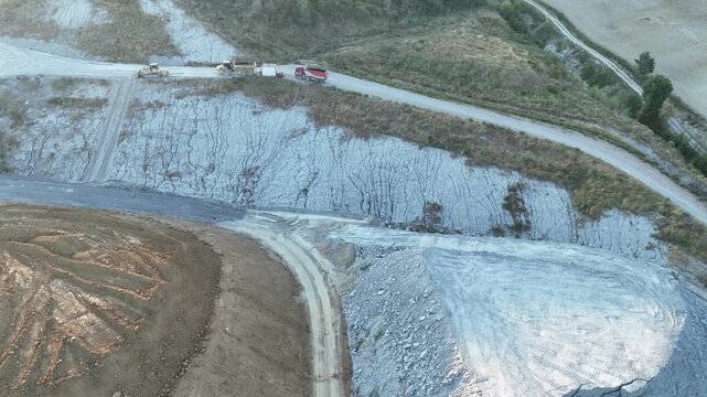 Marl quarry exposes broad stepped excavation areas in the Arda Valley near Vernasca, Piacenza, Emilia-Romagna, Italy, supplying raw material for cement production, aerial shot
