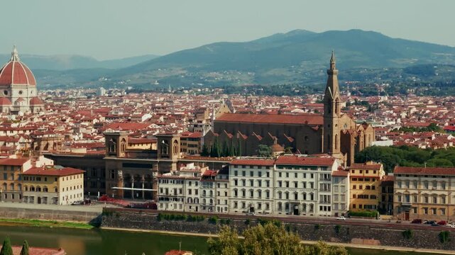 Bell towers, the great flank of Santa Croce and the cathedral cupola line the Florence skyline above the Arno in Tuscany. Elevated telephoto, steady panning shot.
