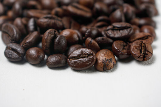 Extreme macro close up shot of dark roasted coffee beans on white background with selective focus