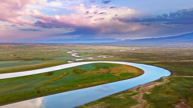 Spectacular aerial footage of a vast meandering river flowing through expansive wetlands at sunset in Bayinbuluke Grassland, Xinjiang, China