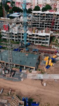 Aerial drone footage of a large residential construction project with multiple unfinished buildings, construction equipment and active development work.
