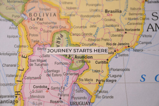 Macro photo of a paper strip reading journey starts here on an Asuncion map