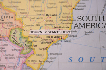 Obraz premium Macro photo of a paper strip reading journey starts here on a Rio map