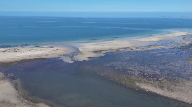 Aerial view of the estuarine outlet at Altona Coastal Park, featuring shallow tidal sandbars, exposed mudflats meeting the deep blue expanse of Port Phillip Bay. Melbourne, Australia