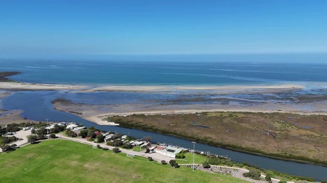 Aerial view of mouth of Kororoit Creek meets Port Phillip Bay. Sport ovals, historic fishing shacks and boat sheds, saltmarsh wetlands, and intertidal sandbars at Williamstown, Melbourne Australia