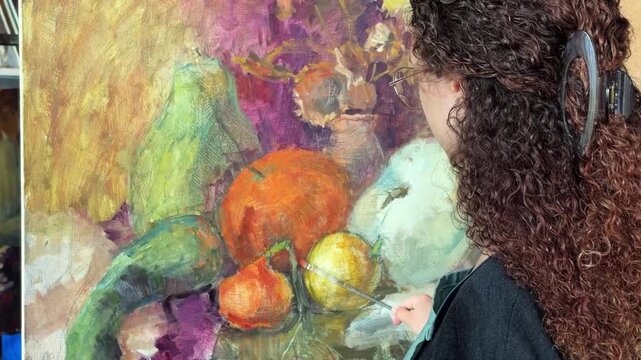 close-up of a painting and female artist paints an autumn still life with pumpkins
