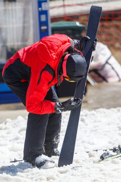 Skier in red jacket bends over snow