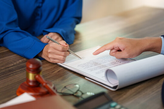 Client signing legal document or contract during consultation with lawyer in office