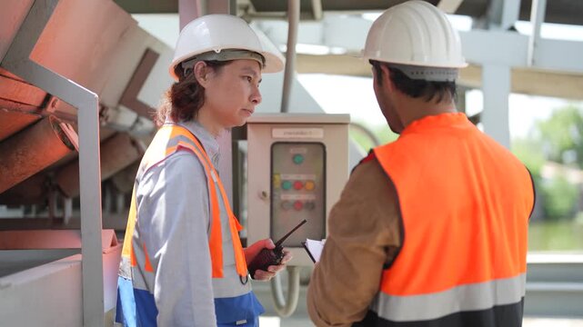 Engineers inspect control panel and operating system during sluice gate maintenance, checking trash removal equipment at water management and drainage facility.