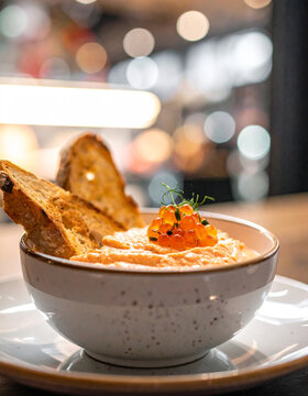 Appetizing smoked salmon dip in bowl, creamy texture with salmon bits, toasted bread, tasty snack. Delicious food. Cooking and culinary concept. Close-up.