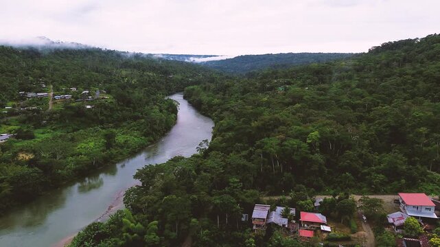 Wide Aerial View of Remote Tropical River Bend in Ecuador with Dense Rainforest, Green Hills, Brown Water and Rural Amazon Landscape