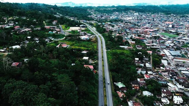 Aerial View of Straight Highway Through Tropical Ecuador Town, Dense Green Forest, Urban Buildings and South American Infrastructure Landscape