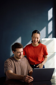 Happy multiracial couple using computer at home.