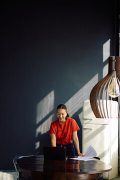 Happy Korean woman working on laptop at home.
