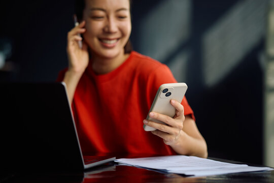 Close up of woman using smart phone while working at home.