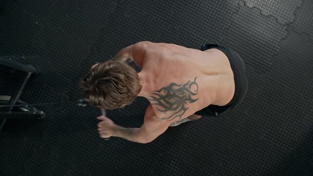 Young adult Caucasian man performing cable rows on gym machine in high angle shot. Clip suitable for fitness marketing, bodybuilding apps, and sport motivation campaigns