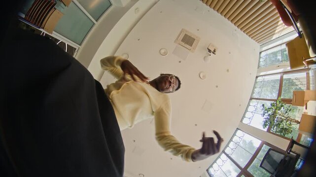 African American young woman dancing energetically and gesturing at low angle fisheye camera in modern office. Video is ideal for youth marketing and social media app advertisements