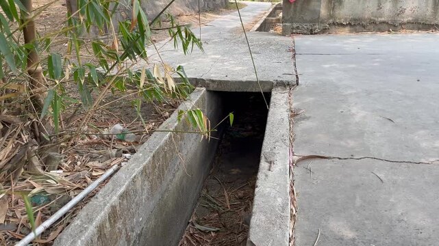 Concrete water canal and culvert drainage next to rural pathway