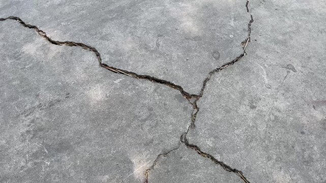 Top view of deep cracks on weathered concrete floor surface