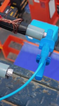 Close up video of a blue test clip attached to a twisted aerial cable conductor for insulation testing, industrial electrical power grid maintenance