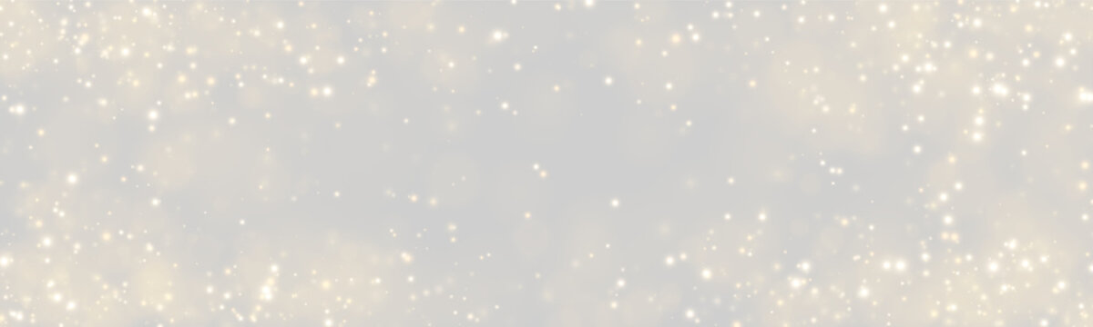 Gleaming golden particles create a sparkling bokeh effect across a dark background. The light dots vary in size and intensity, creating a sense of depth and softness.