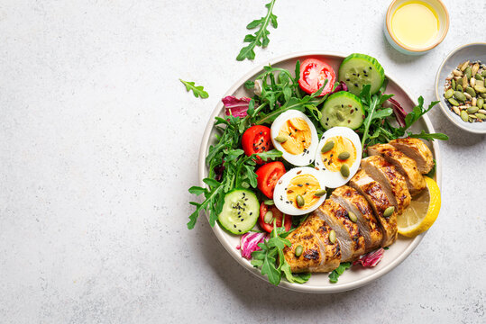 High protein lunch bowl with chicken, eggs and vegetable salad.