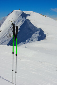 Hiking poles on the wonderful snow-covered ridge to the Pizzo Baciamorti Alpine peak. Orobie Prealps, Lombardy, Italy.