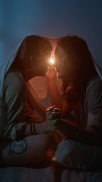 Vertical shot of young adult Caucasian couple sitting under blanket, holding hands and showing affection. Footage ideal for dating apps, Valentine campaigns, and relationship storytelling