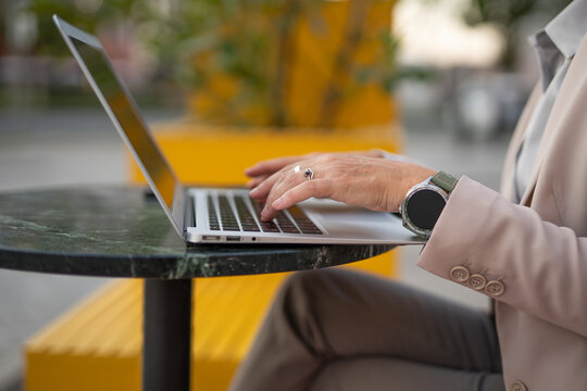 Businesswoman typing on laptop in outdoor cafe working remotely