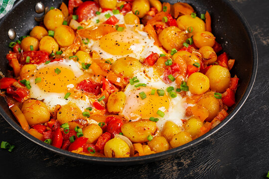 Fried Eggs with Baby Potatoes and Bell Pepper Skillet on Dark Background. Closeup