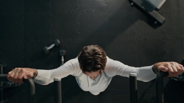 Caucasian athletic man doing pull up exercises on gym equipment captured from top view. Ideal for fitness mobile apps, athletic training campaigns, workout tutorials, and sports marketing