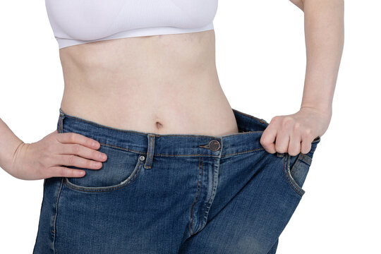 Woman wearing oversized jeans after weight loss. Female torso showing slim waistline with big denim pants. Healthy lifestyle, diet success and body transformation concept. Fitness result