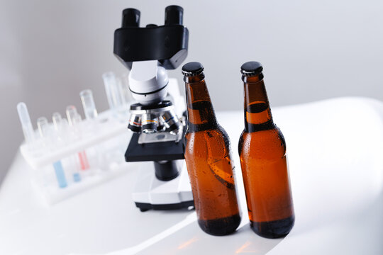 Pair of beer bottles with condensation next to a microscope and test tubes in a laboratory for testing research and quality control