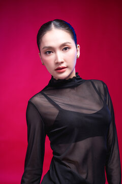 A captivating beauty portrait with the head tilted, direct gaze meeting the camera, elegant neckline and sleek updo against a deep red backdrop, blending allure with poise.