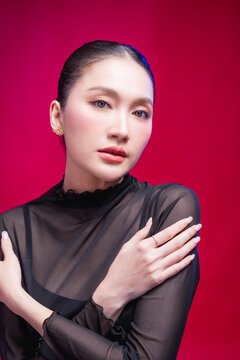 A bold woman points directly at the camera with a confident smirk, dramatic foreground blur and sharp gaze against a vivid red backdrop, radiating attitude and defiance.