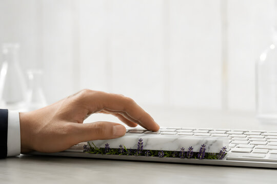 Hand typing on modern keyboard with lavender plants growing from spacebar representing sustainable technology in eco-friendly office environment