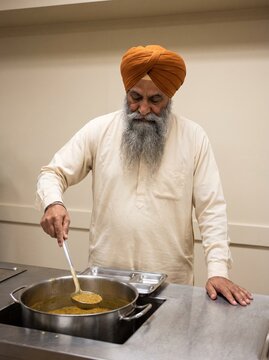 Sikh volunteer serving dal in a community kitchen