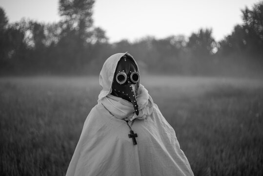 Mysterious masked woman standing alone in autumn Halloween landscape.