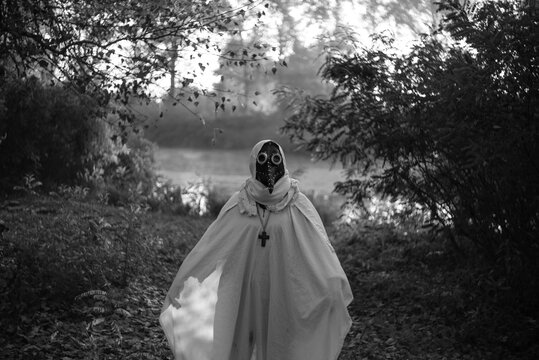 Mysterious masked woman standing alone in autumn Halloween landscape.