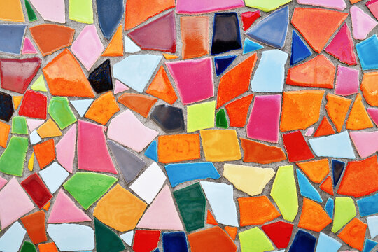 Close up of wall made of irregular small colorful mosaic stones, uneven textured decorative surface with vibrant pattern