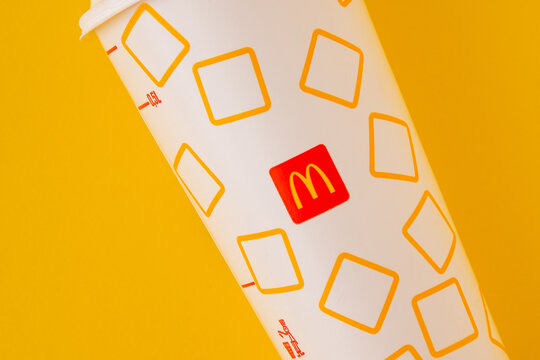 McDonalds paper drink cup with lid on yellow background. White beverage cup for Coca-Cola 0,5L fast food drinks. Kyiv, Ukraine - May 24, 2026