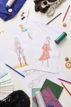 Fashion design papers lie beside fabric swatches, thread, scissors, and pencils. Illustrated garments give workspace thoughtful, creative atmosphere centered on styling and pattern ideas.