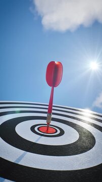 Low angle perspective of Red dart arrow hit bullseye target center with bright sunlight and blue sky. Performance and accuracy concept, 3D animation.